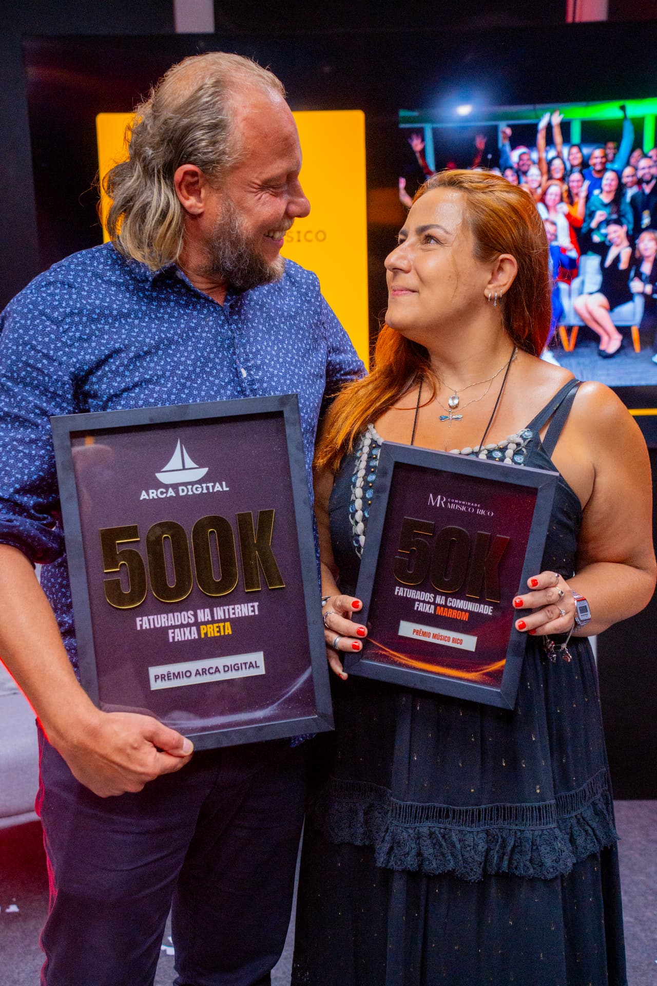 Casal segurando placas de reconhecimento durante o evento